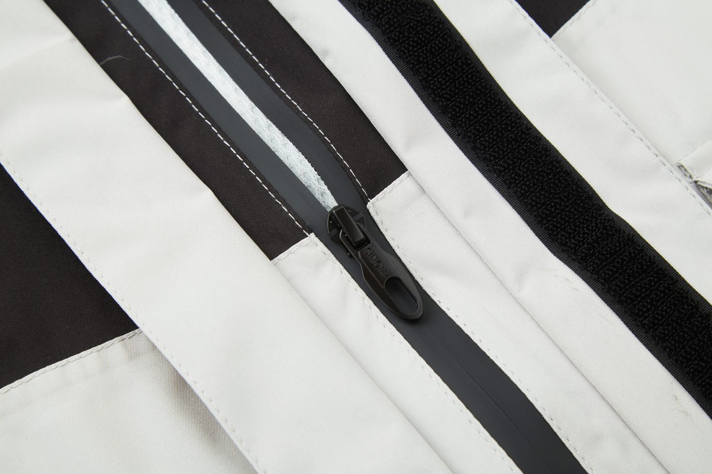 Waterproof zipper behind taped placket and hook-and-loop storm flap
